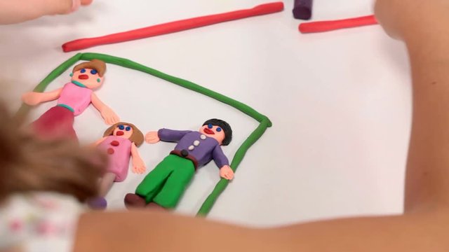 Child making a happy family house from plasticine - over the shoulder shot