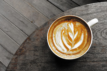 cup of latte art coffee on wooden background