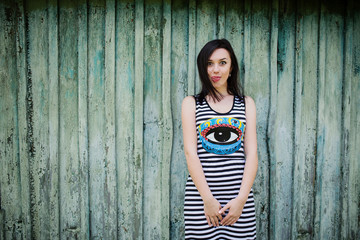 Fototapeta premium Brunette model girl at dress with stripes showing tongue backgro