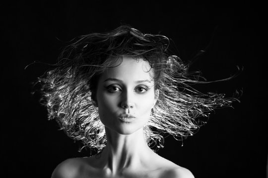 beautiful woman with flying wet hair on black background, monochrome