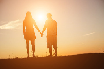 Fototapeta premium silhouette of a man and woman holding hands with each other, wa