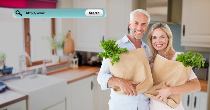 Smiling couple in kitchen holding grocery bags