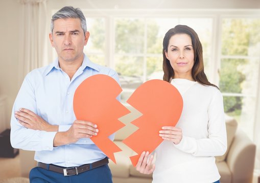 Couple holding a broken heart in a living room