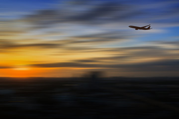 Fototapeta na wymiar Silhouette of airplane flying in a sky over the city at sunrise