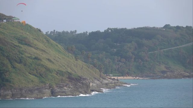 Two persons are paragliding near wind mill. Great landscape view with sea shore and sportsmen in slow motion full HD footage 1920x1080.
