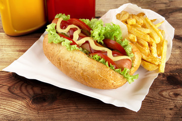 Single hotdog with french fries on tray on plank