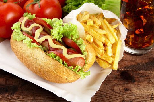 Single hotdog with french fries on tray with cola on plank