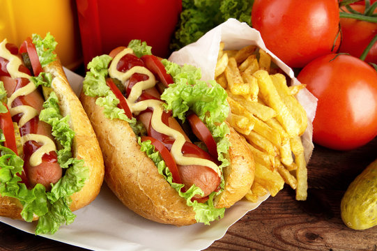 Hotdogs on plate with cola, french fries on wooden desk