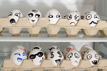 Two trays with painted smiles on the eggs on the refrigerator shelves, close up
