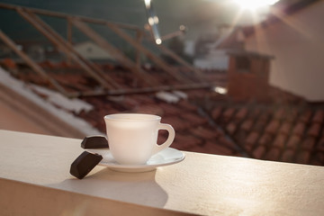 Чашка утреннего кофе на фоне городских крыш.