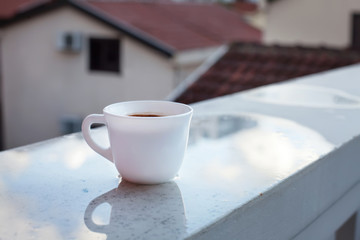 Чашка утреннего кофе на фоне городских крыш.