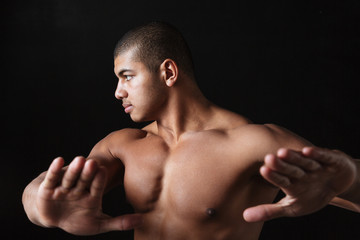 Handsome young african sportsman posing over black background