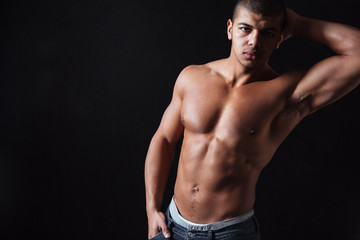 Fototapeta premium Attractive sportsman posing over black background