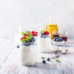 Natural yoghurt with berries on light gray background. Copy space. Healthy breakfast concept.