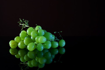 Green grapes on reflective black surface
