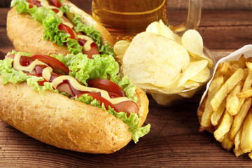 Hot dogs with glass of beer with crisps,french fries on wooden b