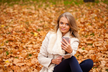 Young beautiful blonde woman in coat reads the message on a cell