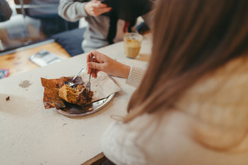 girl with long hair eating a muffin and drinking coffee in cafe