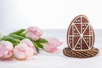 Happy holiday. Easter egg gingerbread and pink tulips on white background