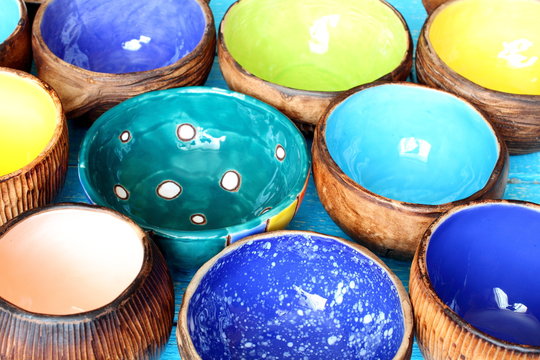 Many different bright multicolored ceramic bowls and cups handcrafted. Background texture