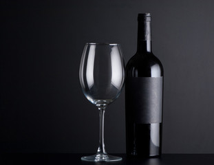 bottle red of wine with a glass on a black background