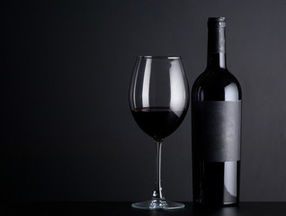 fles rode wijn met een glas op een zwarte achtergrond