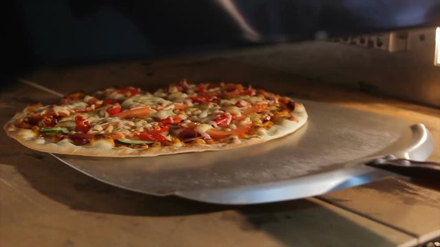 closeup person opens door takes out Italian pizza with special shovel from electrical oven shows dish