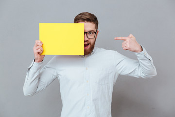 Smiling young bearded businessman holding copyspace blank