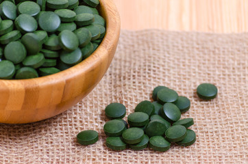 green pills spirulina and chlorella seaweed close up on the wooden
