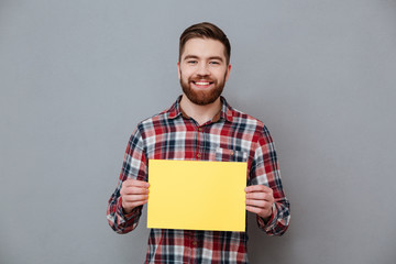 Happy young bearded man holding copyspace blank