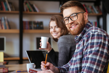 Two happy students with laptop computer networking in library