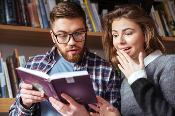 Two smart students reading and studying in library