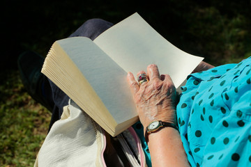 Female hand with wrinkled skin holds open book