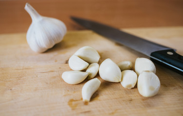 Fresh pealed garlic on wooden cutting board for food.