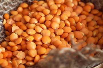 Closeup of raw uncooked red lentils in burlap bag