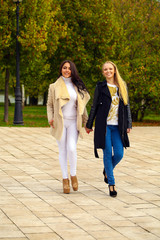 Fototapeta premium Two Young beautiful women walking in park