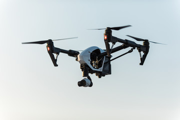 Fototapeta na wymiar White drone with digital camera flying on sky background