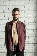 slim bearded man in purple shirt on brick wall background