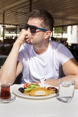 Handsome young man  drinking tea and having breakfast 