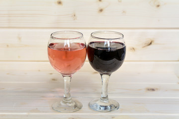 Glasses of red wine and rose isolated on a wooden  background