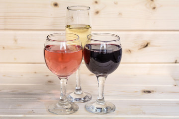 Glasses of red wine,rose and champagne isolated on a wooden  background