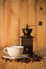 Manual coffee grinder and  cup of coffee on  wooden surface