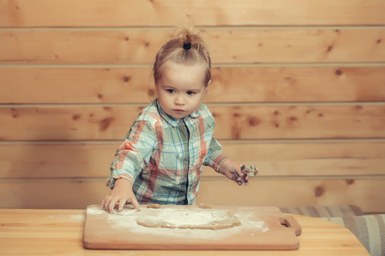 cute child cooking with dough and flour, holds metallic mold