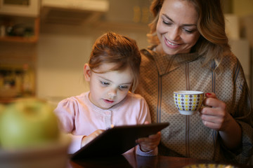 Mother and daughter reading from tablet.