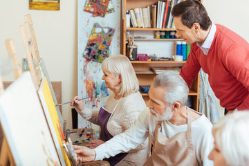 Handsome artist controlling his colleagues in painting class