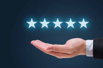 Businessman hand holding five stars isolated on blue background