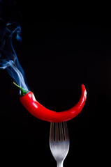 smoking chili pepper on fork on black background - 135572924