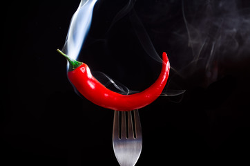 smoking chili pepper on fork on black background - 135572938
