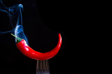 smoking chili pepper on fork on black background - 135572950
