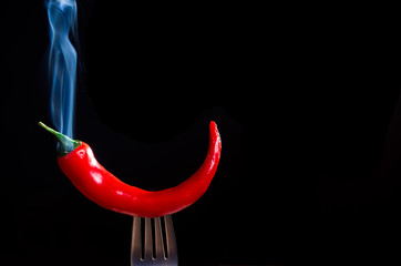 smoking chili pepper on fork on black background - 135572958